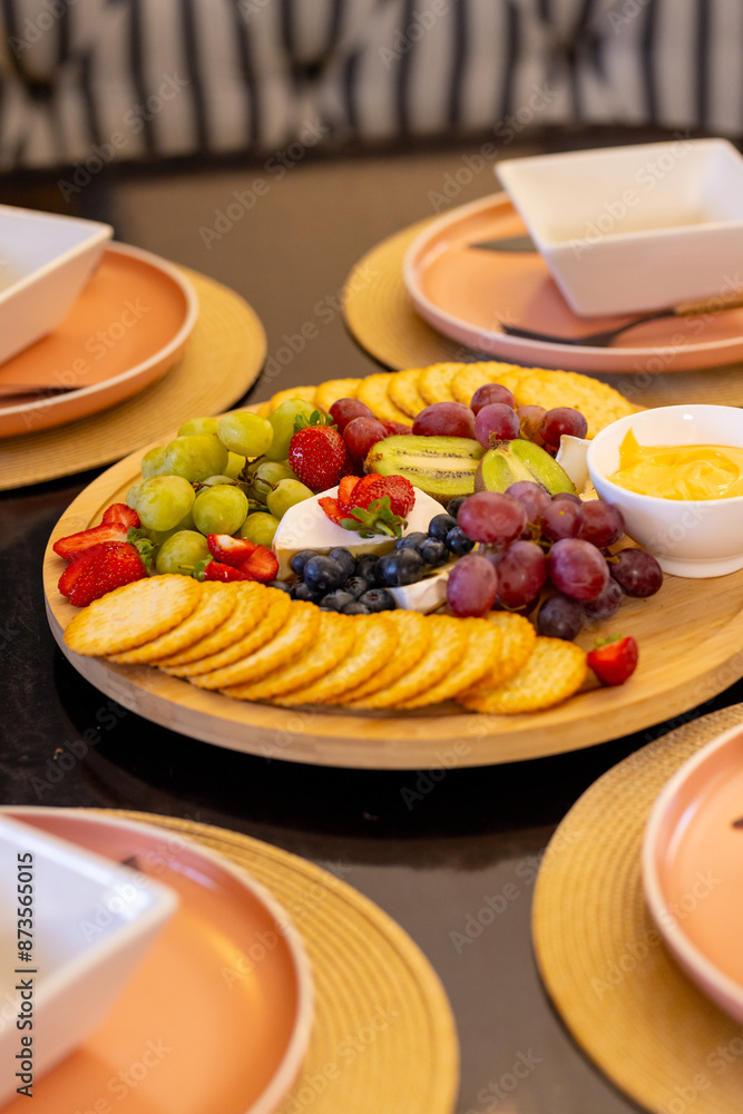 Serving colorful fruit and cracker platter on dining table for diverse friends, copy space Serving colorful fruit and cracker platter on dining table for diverse friends, copy space