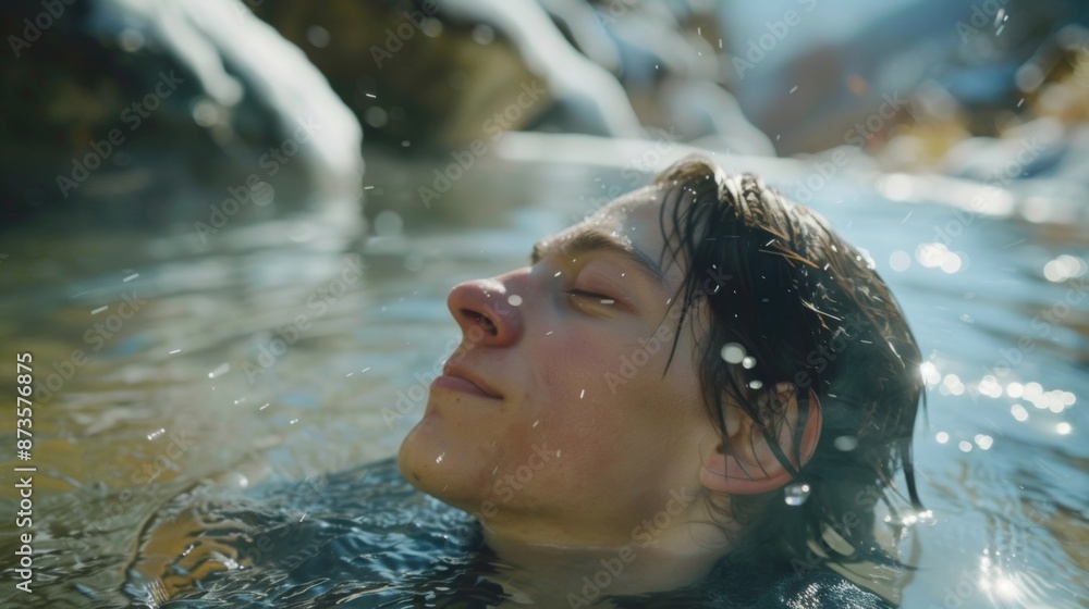 A person sitting in a scenic alpine hot spring eyes closed and head tilted back as they enjoy the cold mountain air and cold water on their skin promoting longevity. A person sitting in a scenic alpine hot spring eyes closed and head tilted back as they enjoy the cold mountain air and cold water on their skin promoting longevity.