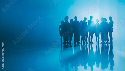 Silhouetted group of diverse people in backlit blue setting, symbolizing teamwork, unity, and collaboration. © sornram