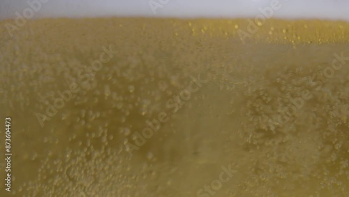 Rippling beer foam and bubbles in a glass filmed in slow motion.