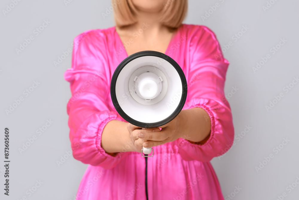 Fototapeta premium Mature woman with megaphone on grey background