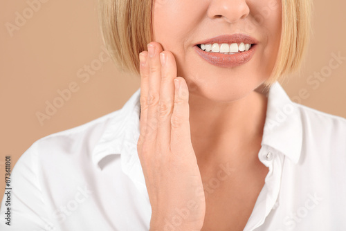 Beautiful mature woman suffering from toothache on brown background,closeup