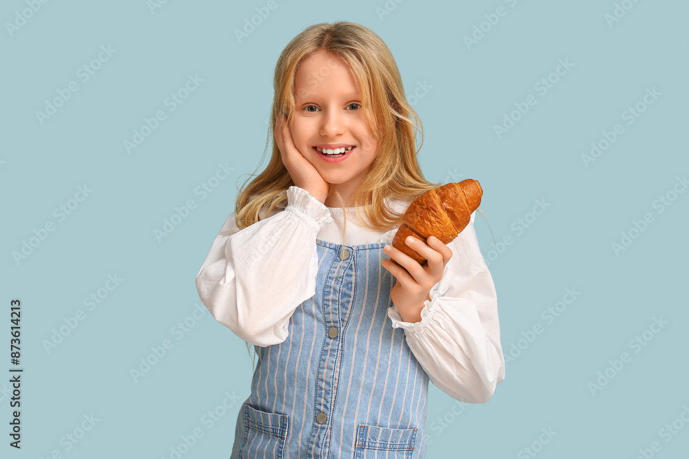 Emotional little girl holding tasty croissant on color background Emotional little girl holding tasty croissant on color background
