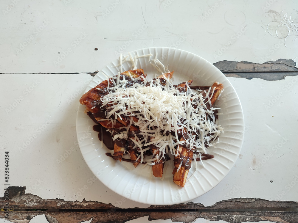 Fototapeta premium Grated cheese on toast on a plate at the table. Roti bakar. 