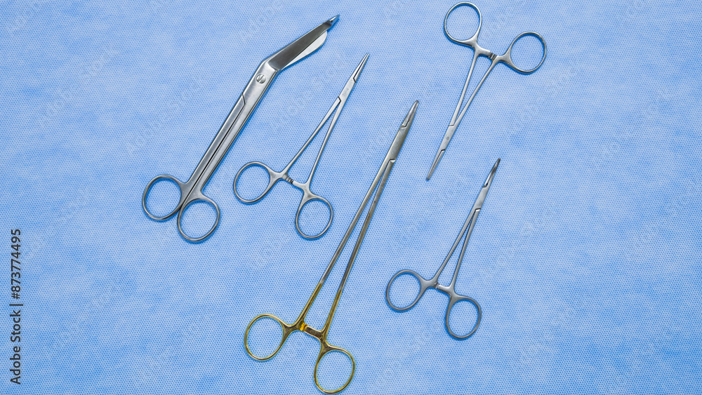 Fototapeta premium Flat lay of stainless forceps medical scissors placed on a blue background. Medical instruments . Medical Surgical Instrument. Equipment used in surgery.