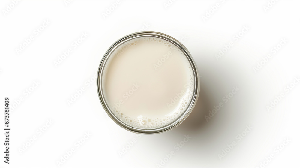A glass full of fresh milk, viewed from above against a neutral white background, exudes freshness and appetizing appearance.