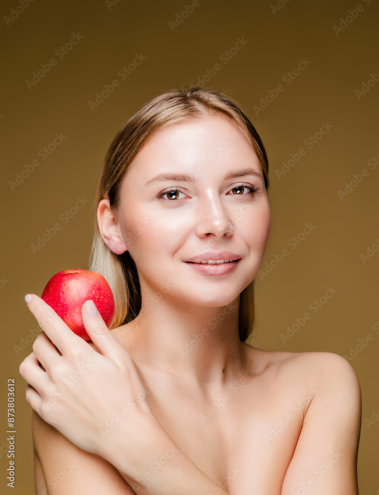 Woman Holding Apple on Brown Background. A young Caucasian woman with smooth, glowing skin holding an apple against a brown background, symbolizing health and vitality. Woman Holding Apple on Brown Background. A young Caucasian woman with smooth, glowing skin holding an apple against a brown background, symbolizing health and vitality.