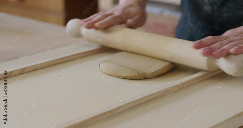 Preparing clay for pottery, rolling with a wooden roller, flattening the clay. Handheld shot with shallow depth of field Preparing clay for pottery, rolling with a wooden roller, flattening the clay. Handheld shot with shallow depth of field