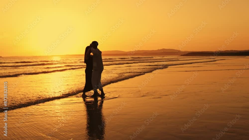 A couple standing on the beach at sunset A couple standing on the beach at sunset