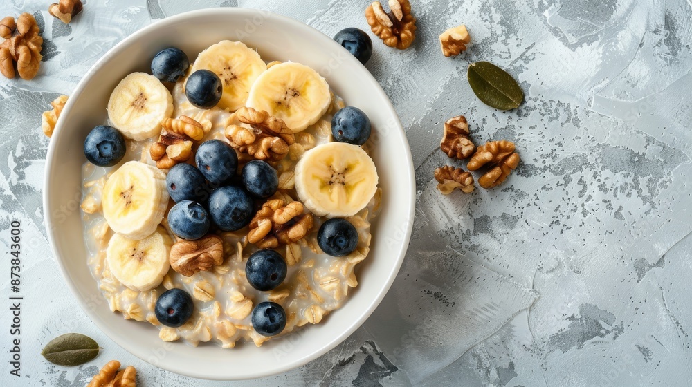 Fototapeta premium A bowl filled with oatmeal topped with fresh blueberries and crunchy walnuts. The concept of a healthy breakfast.