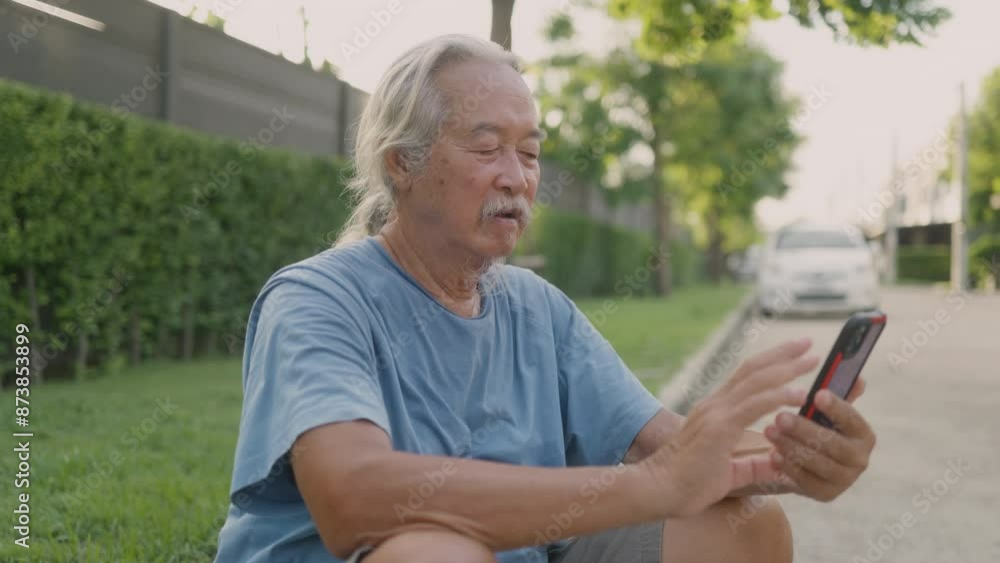Asian senior man sitting on the grass using smart phone. Asian senior man sitting on the grass using smart phone.