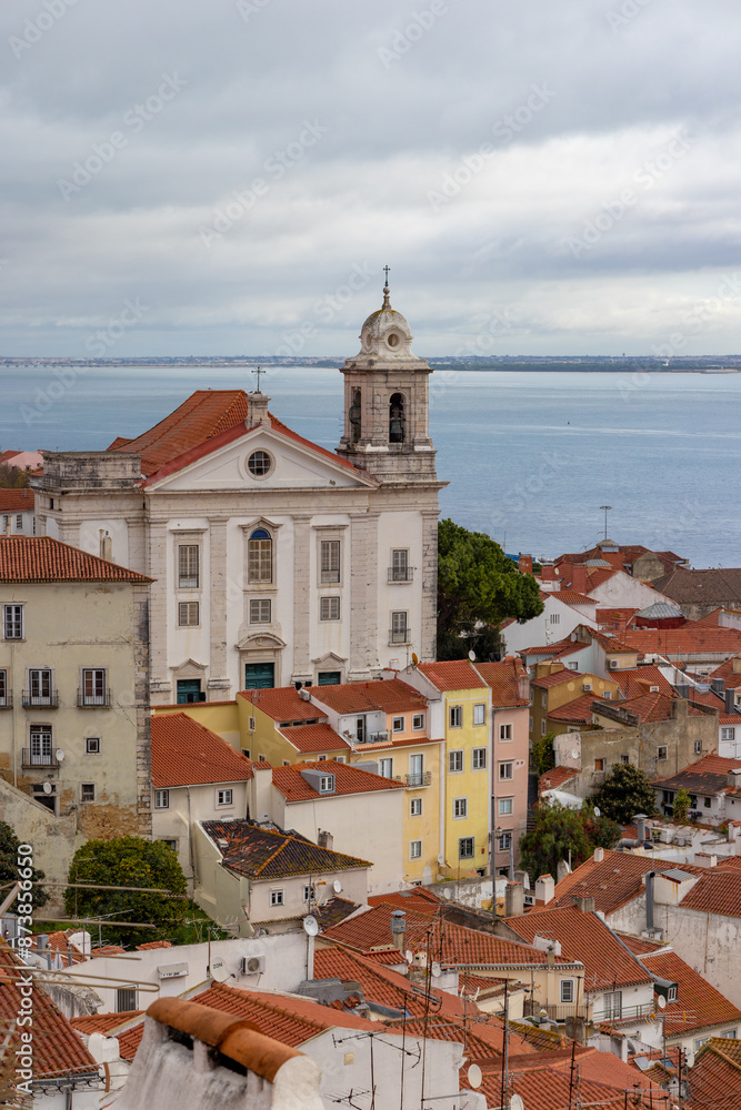 Fototapeta premium Lisbons old town presents a charming scene with classic buildings and a riverside church. The citys European heritage comes alive in its historic architecture and picturesque location