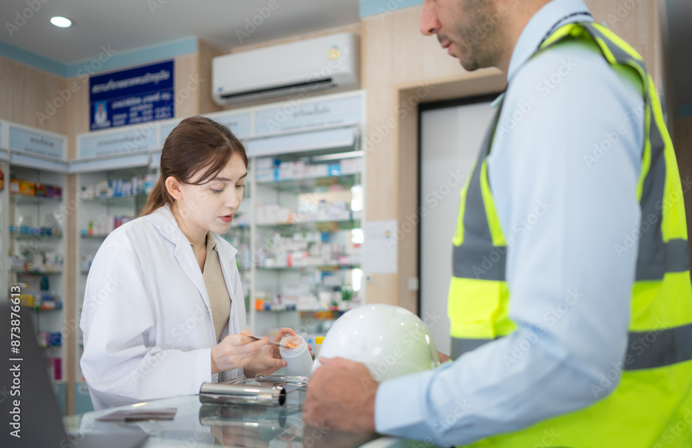 Obraz premium The pharmacist provides medicine to the engineers who come to buy medicine in the pharmacy.