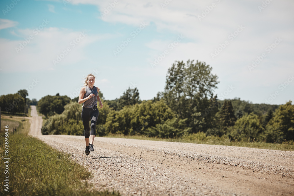 Nature, training and woman running on path at park for healthy body, wellness or fitness to workout. Earphones, cardio and trail runner exercise on road for race, marathon and jog outdoor in summer Nature, training and woman running on path at park for healthy body, wellness or fitness to workout. Earphones, cardio and trail runner exercise on road for race, marathon and jog outdoor in summer