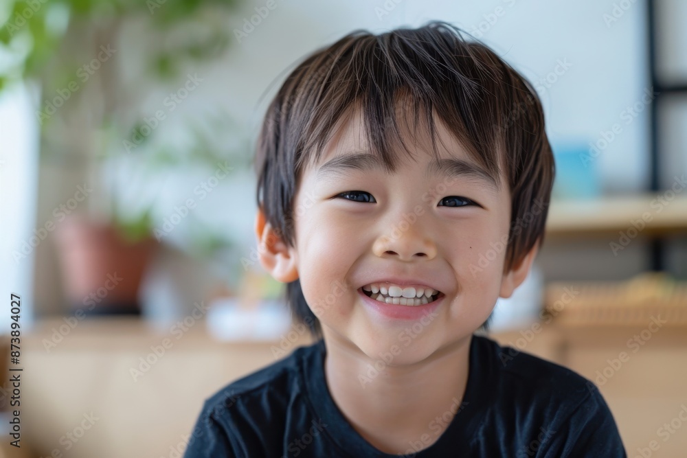A young asian boy with brown hair and a black shirt is smiling. He is wearing a black shirt and has a black hat A young asian boy with brown hair and a black shirt is smiling. He is wearing a black shirt and has a black hat
