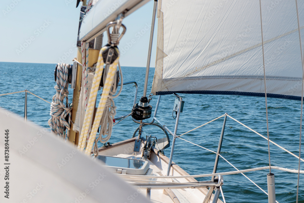 Obraz premium Luxury cruise on a sailing rigged yacht under a genoa sailing in a light wind during the regatta. Yachting as a luxury sport and great vacation. View from the deck to the bow, mast, sails.