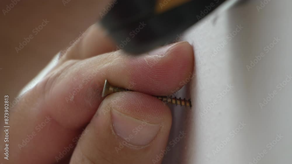 A man hands using a power tool fastens a board with a screw. Slow motion A man hands using a power tool fastens a board with a screw. Slow motion