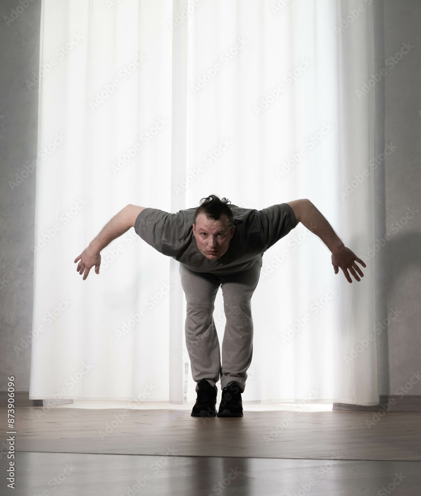 Fototapeta premium Dance in motion, pose of a man in hip-hop style clothes. Sports dancing guy in training poses. Dance training at home.