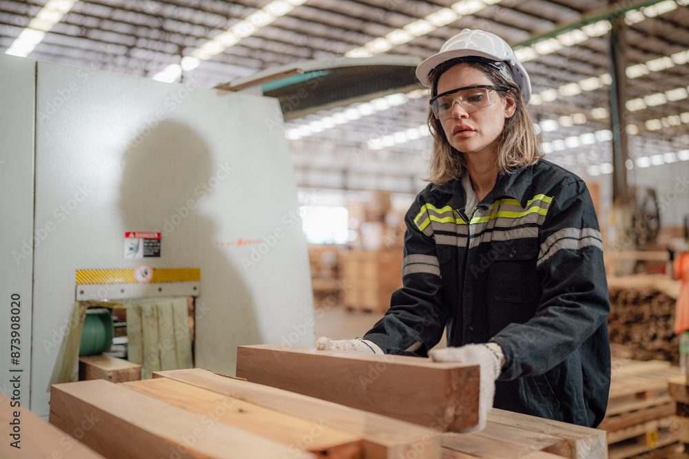 Confident female worker standing in lumber warehouse of hardwood furniture factory inspecting production machine. Serious female technician, engineer busy working with tool in woodwork manufacturing. Confident female worker standing in lumber warehouse of hardwood furniture factory inspecting production machine. Serious female technician, engineer busy working with tool in woodwork manufacturing.