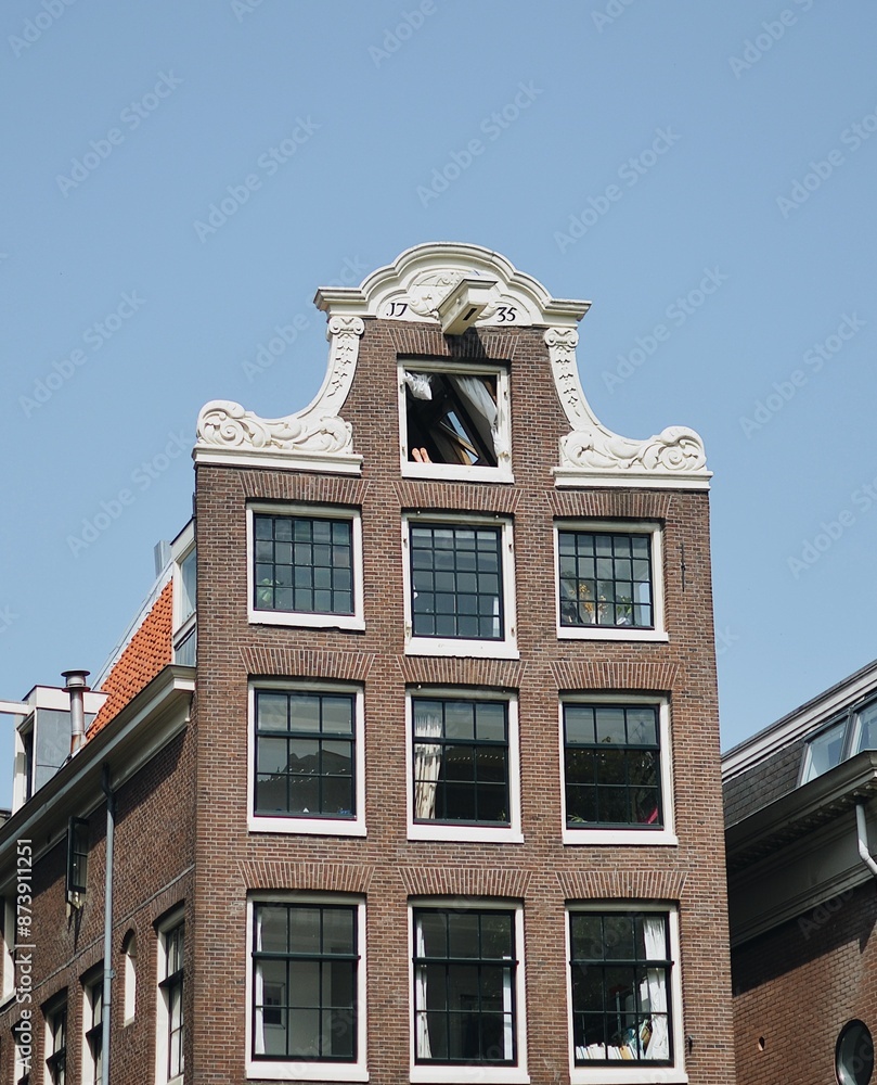 Fototapeta premium building in amsterdam with someone showing theitr feet in the window resting