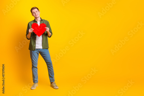 Photo of handsome nice man wear khaki clothes hold heart empty space isolated on vivid yellow color background