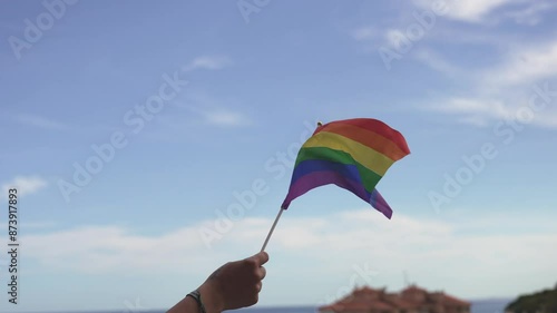 Person waving rainbow lgbt on a balcony.