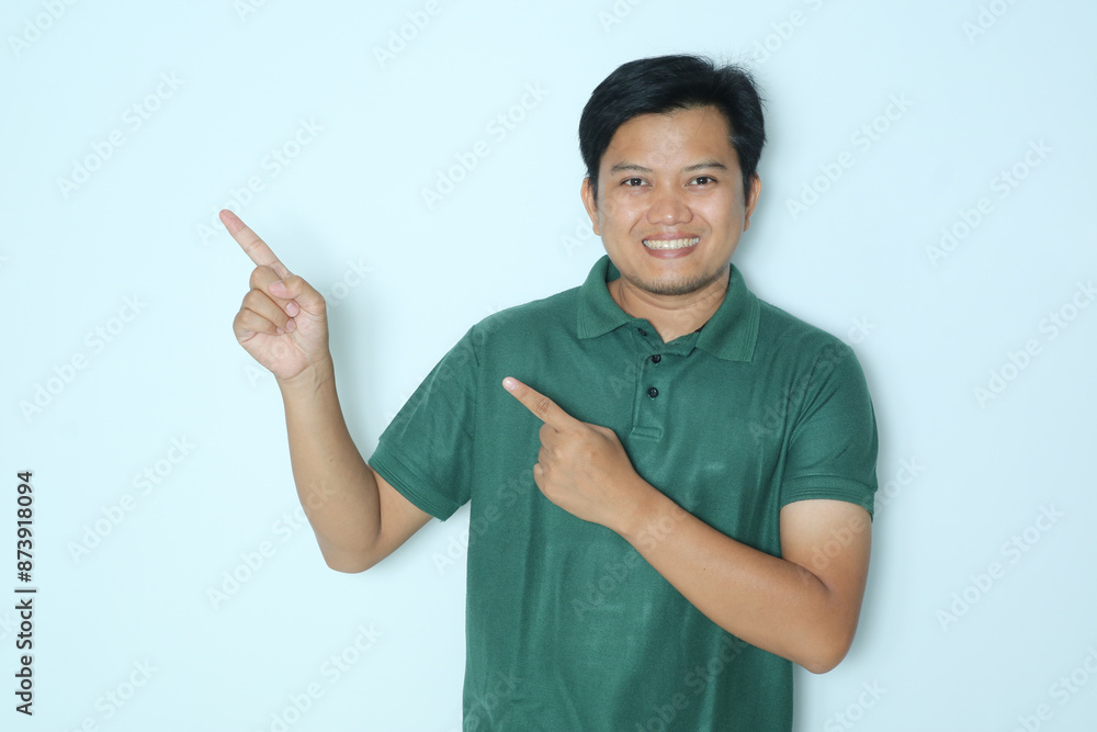 Young Asian man pointing to the right side with excited expression. Wearing a green a shirt Young Asian man pointing to the right side with excited expression. Wearing a green a shirt
