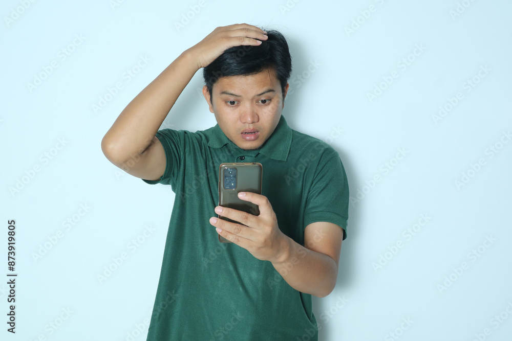Asian man showing sad expression looking at smartphone. Wearing a green t-shirt Asian man showing sad expression looking at smartphone. Wearing a green t-shirt