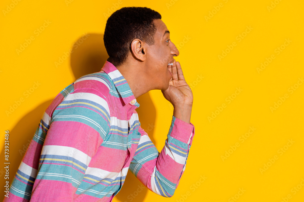 Photo portrait of handsome young guy share secret scream dressed stylish striped garment isolated on yellow color background Photo portrait of handsome young guy share secret scream dressed stylish striped garment isolated on yellow color background
