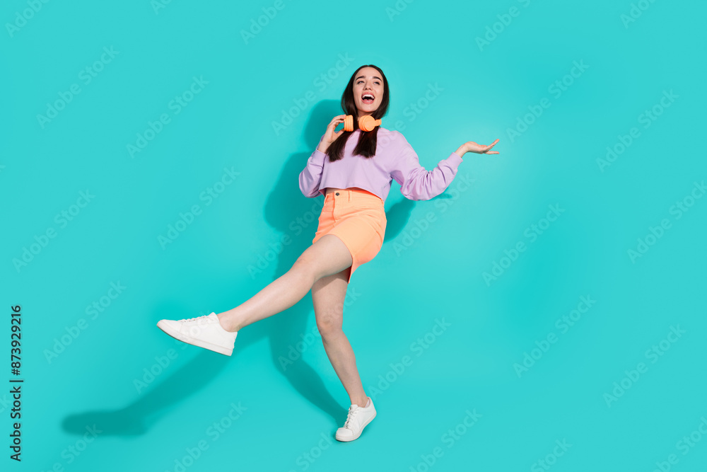 Full length photo of adorable lovely girl wear short skirt having fun empty space isolated turquoise color background Full length photo of adorable lovely girl wear short skirt having fun empty space isolated turquoise color background