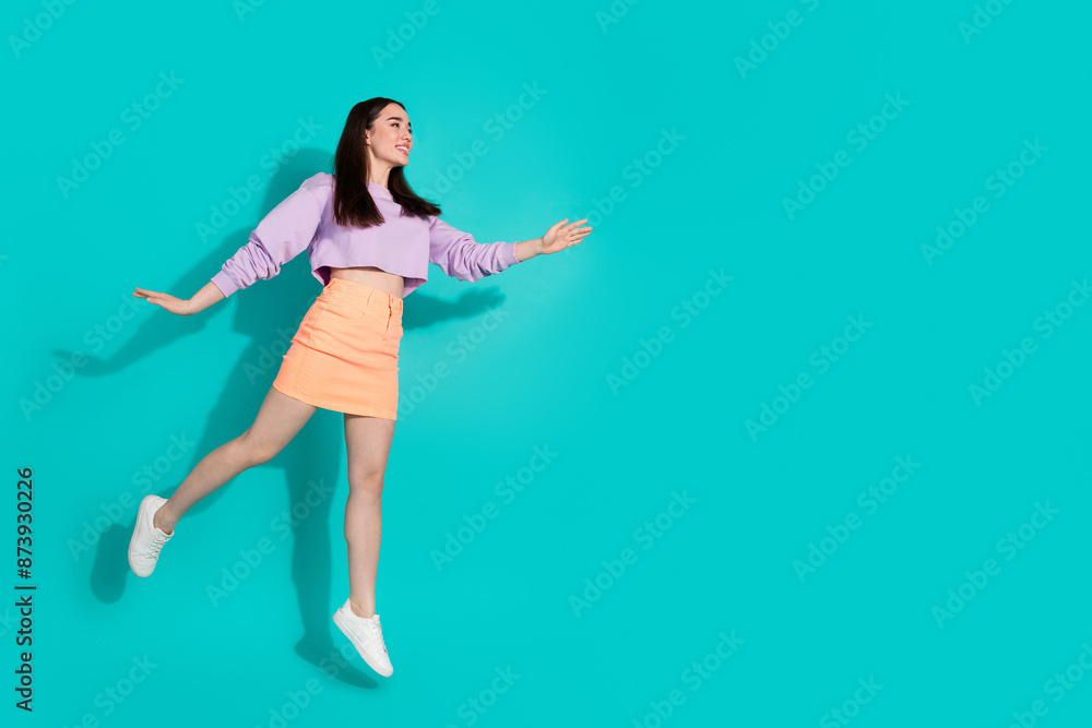 Full length photo of shiny attractive lady dressed mini skirt jumping high looking empty space isolated blue color background Full length photo of shiny attractive lady dressed mini skirt jumping high looking empty space isolated blue color background