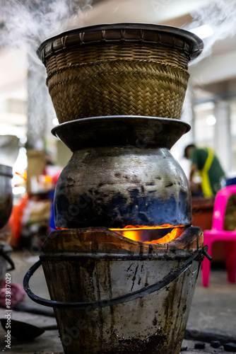 Wallpaper Mural Stacked.  Wicker cooking pot stacked on a metal pan over an open flame in a Bangkok market.  Blurrred background. Torontodigital.ca
