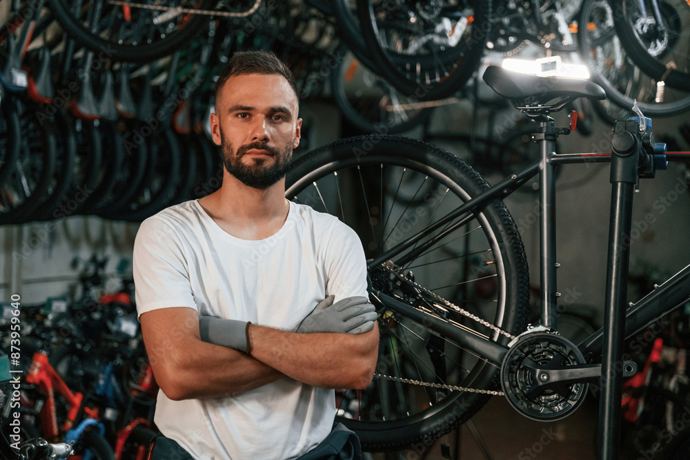 Standing with arms crossed, portrait. Repair man in bicycle shop, working in store Standing with arms crossed, portrait. Repair man in bicycle shop, working in store