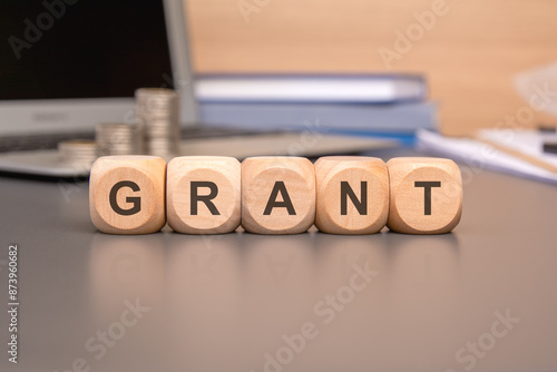 GRANT written on a wooden cube in office desk photo