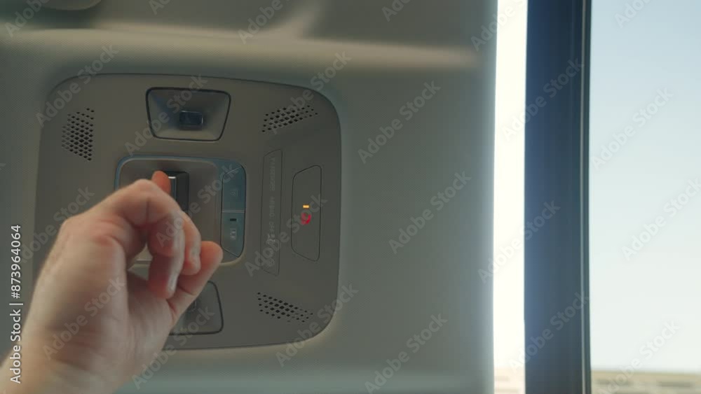 man hand confidently presses sleek button, causing the sunroof hatch of the car to smoothly slide open, inviting gentle breeze into the vehicle interior. man hand confidently presses sleek button, causing the sunroof hatch of the car to smoothly slide open, inviting gentle breeze into the vehicle interior.
