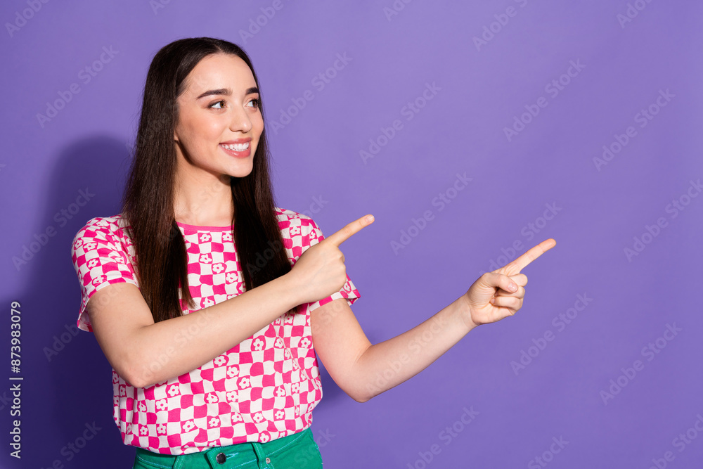 Photo of pretty young woman point fingers empty space wear checkered t-shirt isolated on purple color background