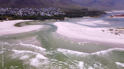 Aerial tilt-up over Klein River estuary mouth as it breaches beach into ocean photo