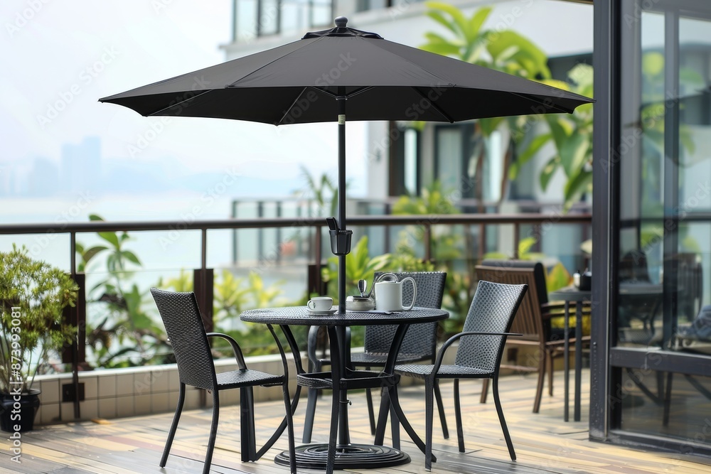 Obraz premium Modern outdoor dining area with black umbrella and city views, creating a stylish and inviting space perfect for enjoying meals and scenic views.