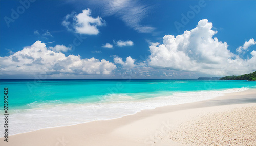 White sand beach and blue ocean shore. Turquoise waters and blue sky with white clouds.