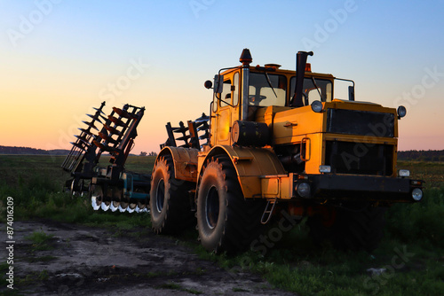 Cultivator on agricultural field at golden hour. Machine in field at sunset.