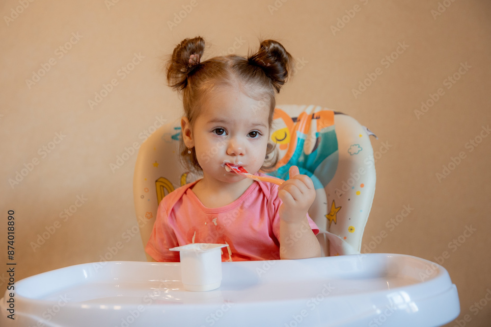 A little girl is sitting on a high chair eating at home A little girl is sitting on a high chair eating at home
