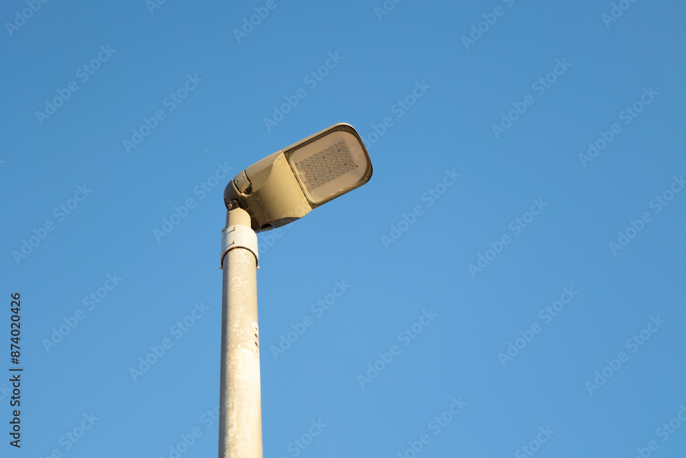 A single streetlight stands tall against a pristine, cloudless blue sky, bathing in daylight, capturing the simplicity and functionality of urban infrastructure. A single streetlight stands tall against a pristine, cloudless blue sky, bathing in daylight, capturing the simplicity and functionality of urban infrastructure.