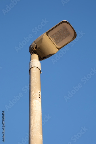 A single streetlight stands tall against a pristine, cloudless blue sky, bathing in daylight, capturing the simplicity and functionality of urban infrastructure.