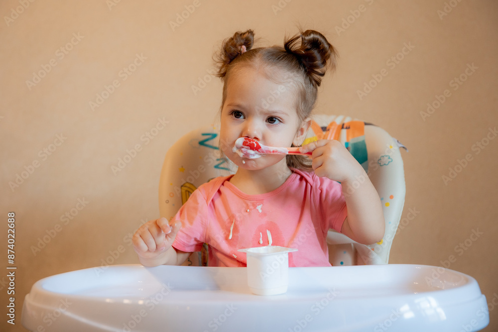 A little girl is sitting on a high chair eating at home A little girl is sitting on a high chair eating at home