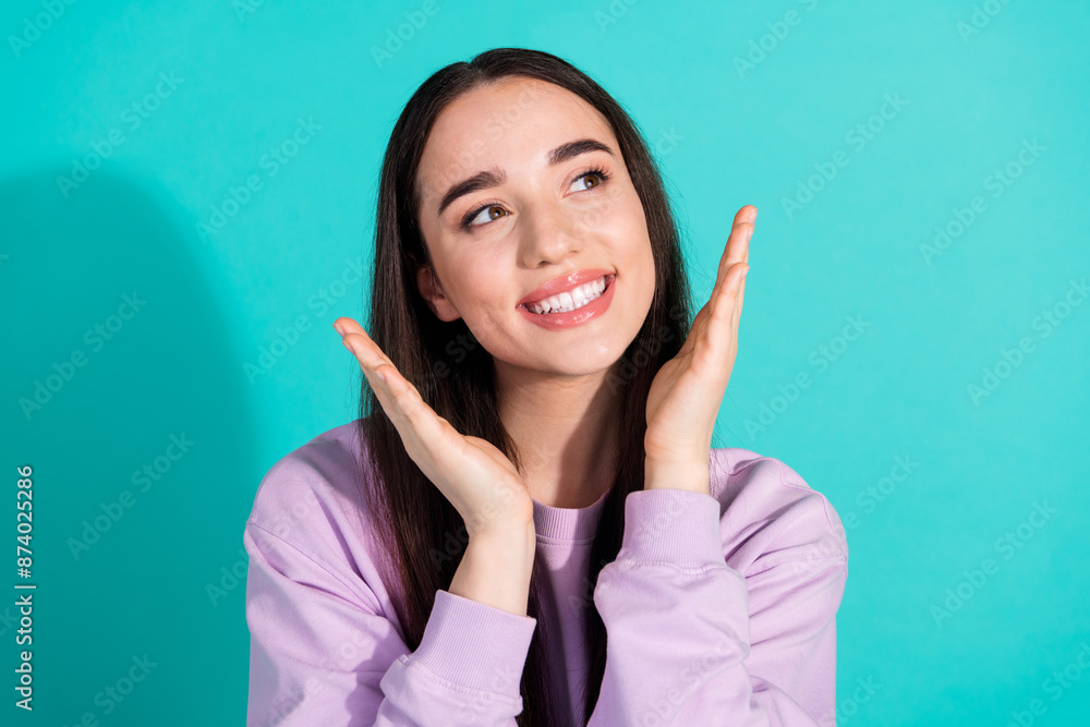 Photo portrait of pretty young girl look empty space raise hands wear trendy violet outfit isolated on cyan color background Photo portrait of pretty young girl look empty space raise hands wear trendy violet outfit isolated on cyan color background