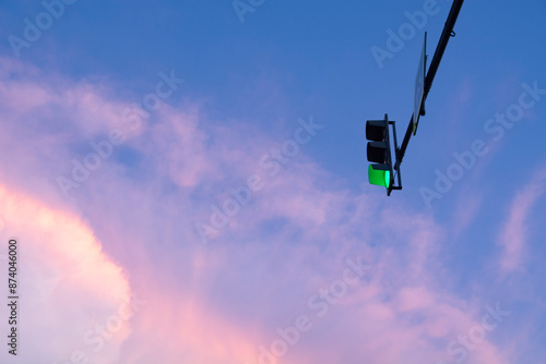 A real majestic background of the sunset sky with delicate multicolored clouds and a traffic light with green light