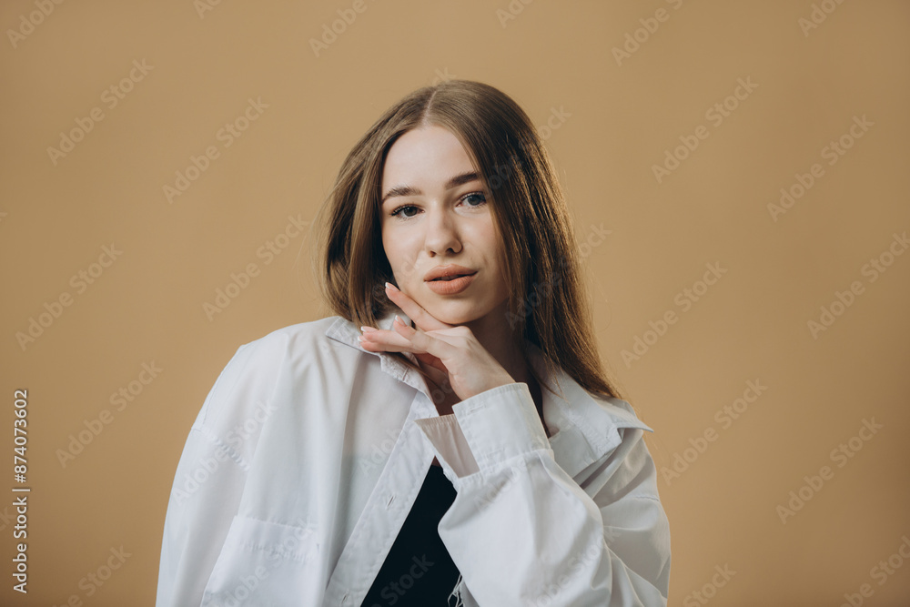 A modern young woman in a fashionable outfit is posing on a beige background. A modern young woman in a fashionable outfit is posing on a beige background.