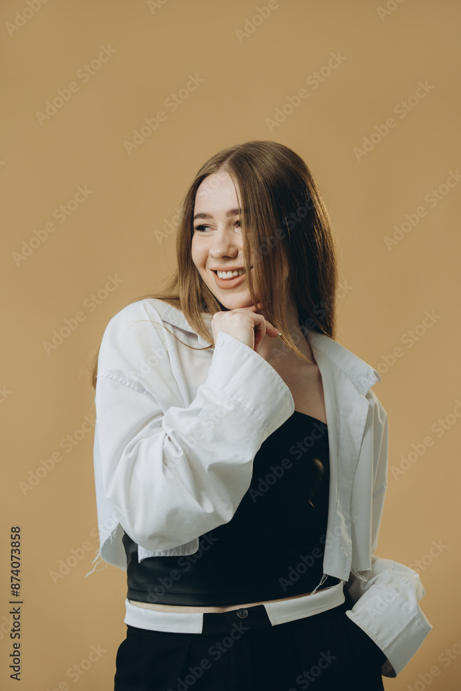 Portrait of a lovely casual girl looking away isolated over beige background.