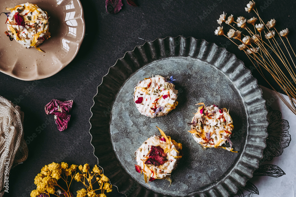 Petits fromages de chèvre frais avec des graines et pétales fait-maison posés dans une assiette