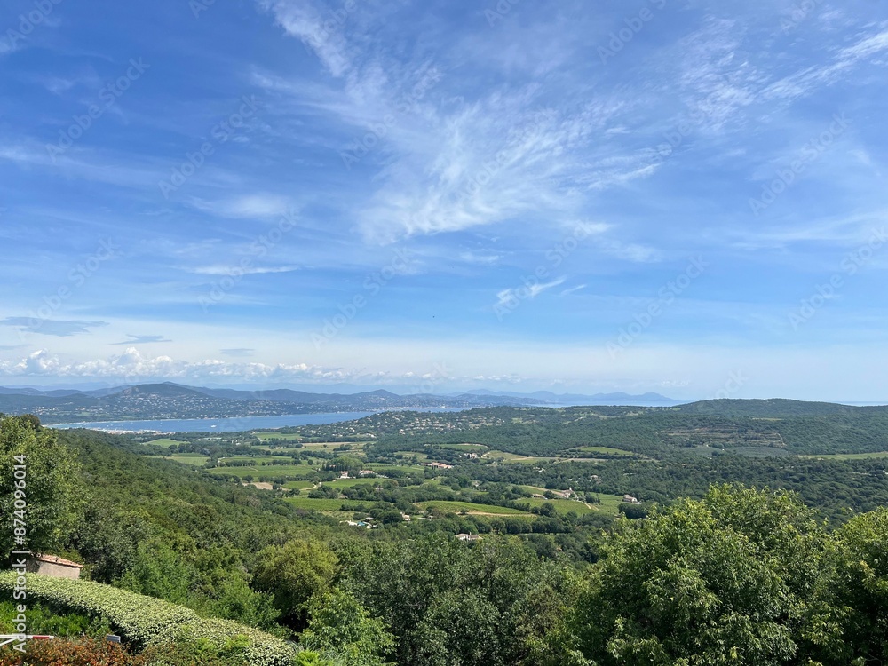 Scenic view of a lush green landscape with mountains and blue sky in the background Scenic view of a lush green landscape with mountains and blue sky in the background
